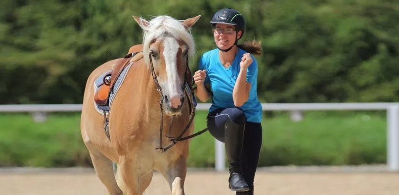 A rider warms herself up before mounting the horse.