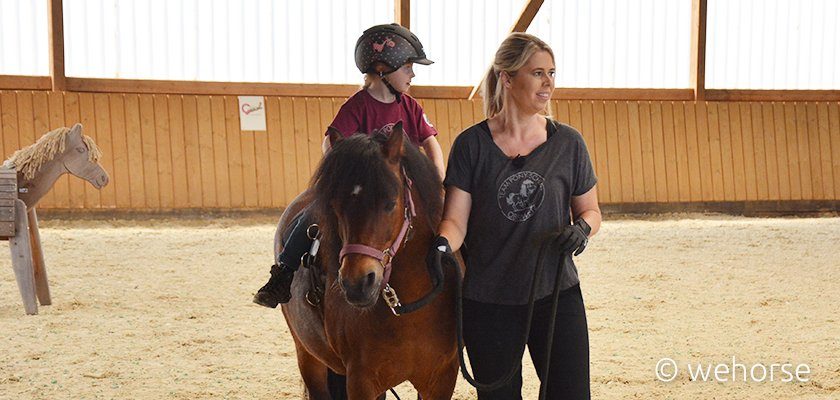 kinderreiten-angst-pony Kolly Holland-Nell führt Pony, darauf sitzt ein Kind.