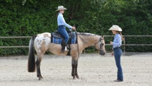 Eine Frau mit Westernausrüstung auf einem Pferd.
