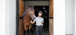 Eine junge Frau führt ein Pferd aus der Stallgasse
