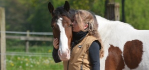 Eine Frau, die ihr Pferd umarmt.